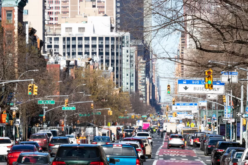 Busy New York city street with red painted bus-only lane on right.